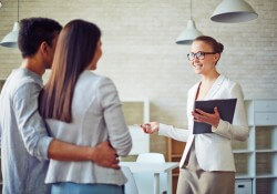 Female broker consulting young couple in realtor office