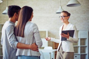 Female broker consulting young couple in realtor office